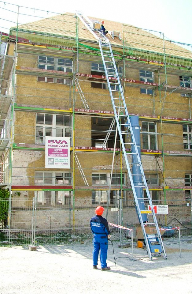 Ein Dachdeckerlift transportiert Dachpfannen auf ein Satteldach