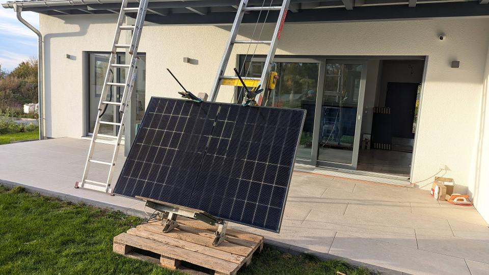 Transport von Solarmodulen auf das Dach eines Bungalows