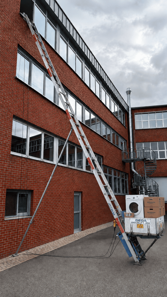Ein Möbellift vor einem rot geklinkerten Gebäude.