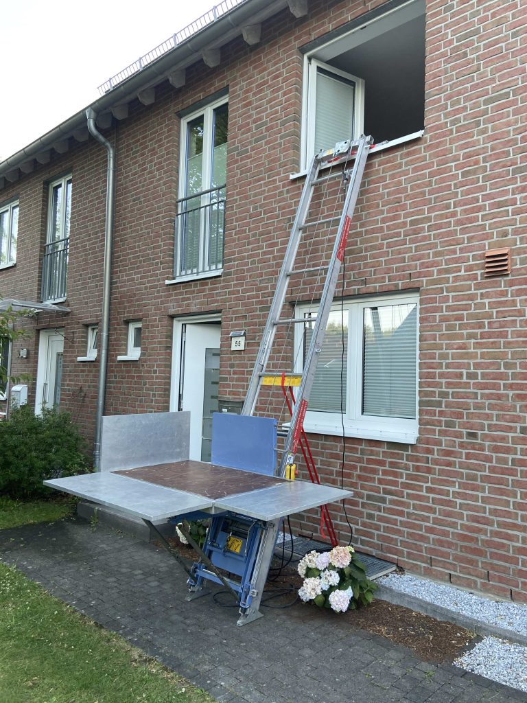 Ein Möbellift mit einer großen Möbelpritsche vor einem Privathaus.